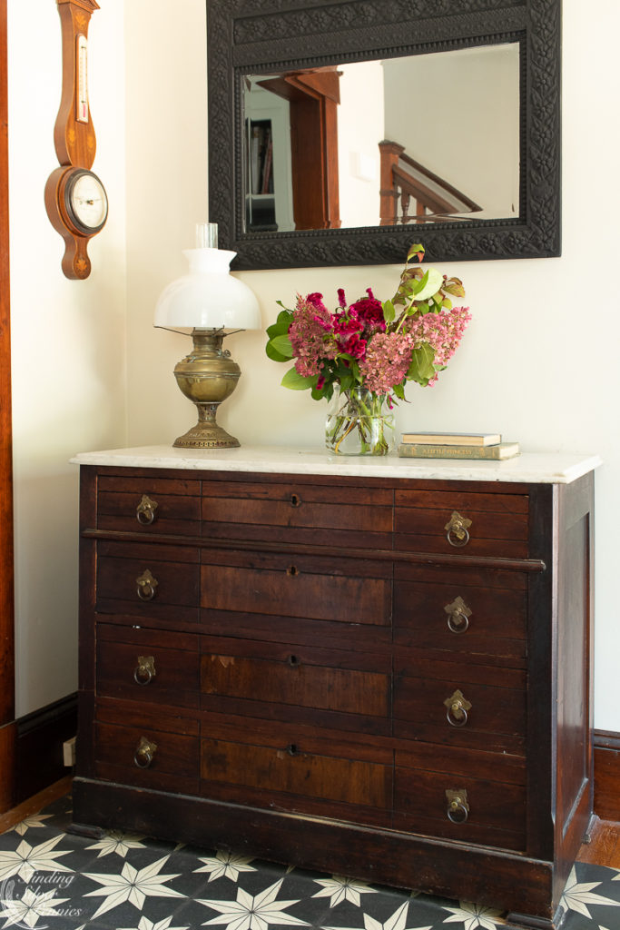 Vintage Dresser with marble top, brass lamp, books and flowers on top.