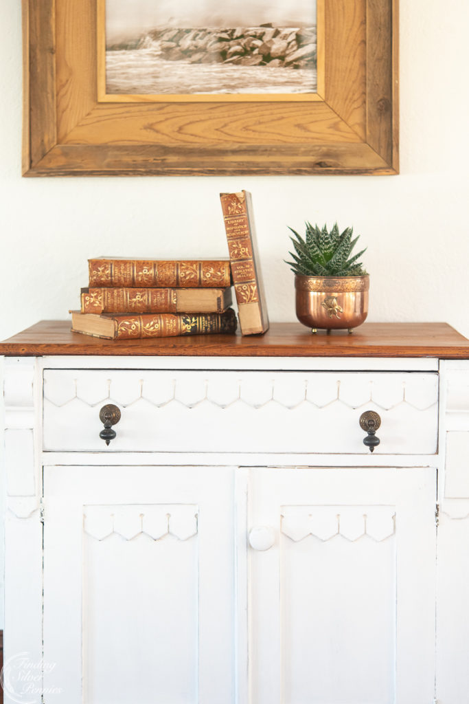 White vintage washstand with books on top and plant