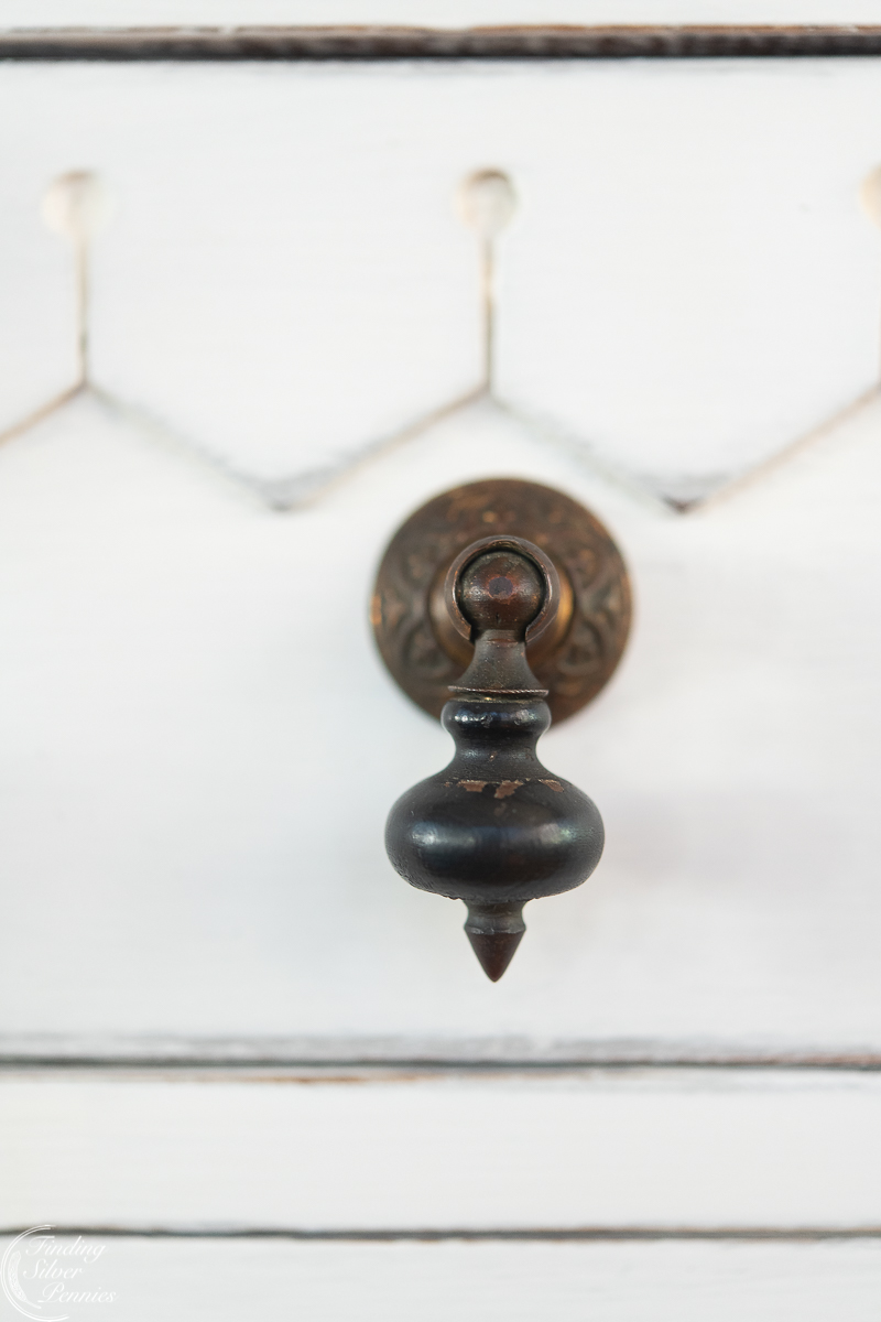 Ornate drawer pull from 1800s on white cabinet